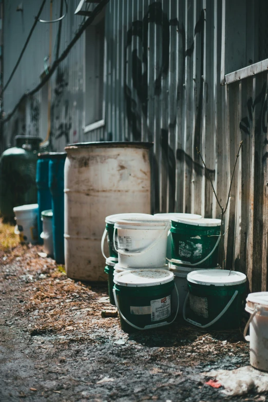 several green and white buckets sit against a metal fence