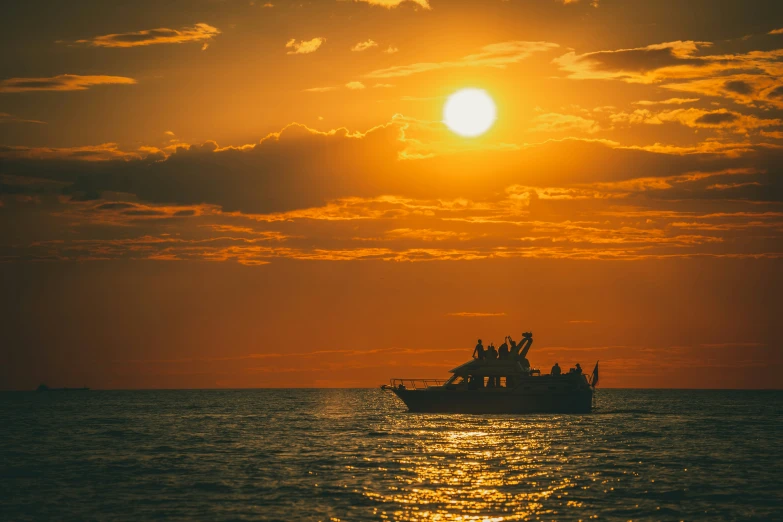 a boat floating in the water with the sun setting