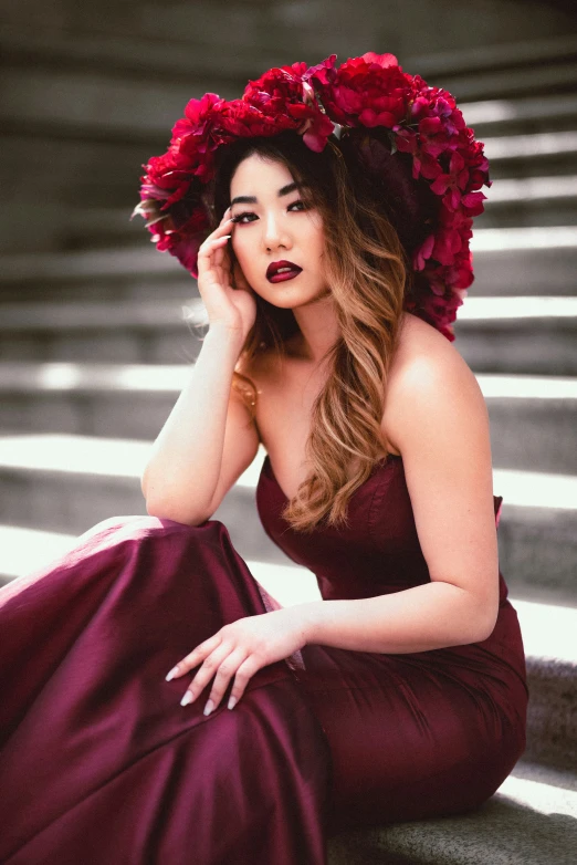 a beautiful young woman in red dress sitting on steps with flowers on her head