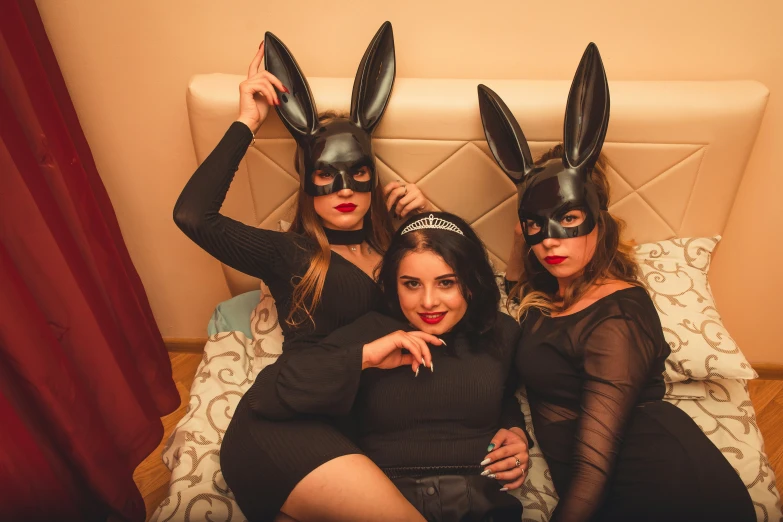 three women with bunny ears sitting on a bed