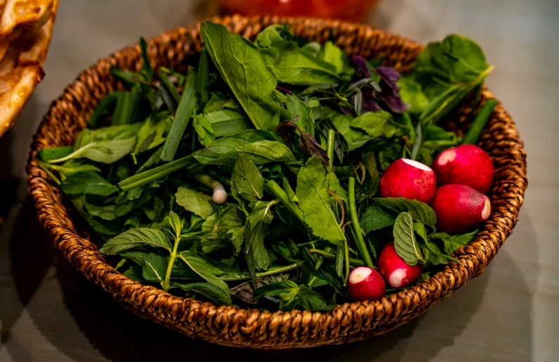 some vegetables in a basket next to some sliced tomatoes