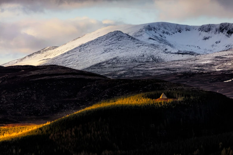 snowy mountains with trees and clouds in the sky