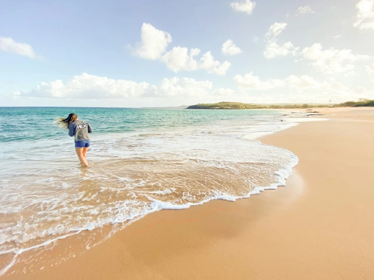 a woman walking along the edge of the ocean