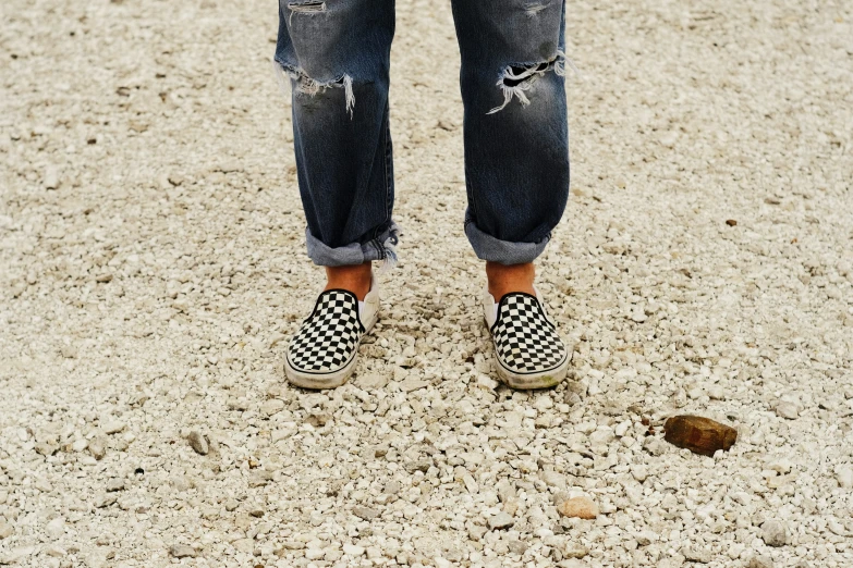 a man standing in a desert wearing plaid vans