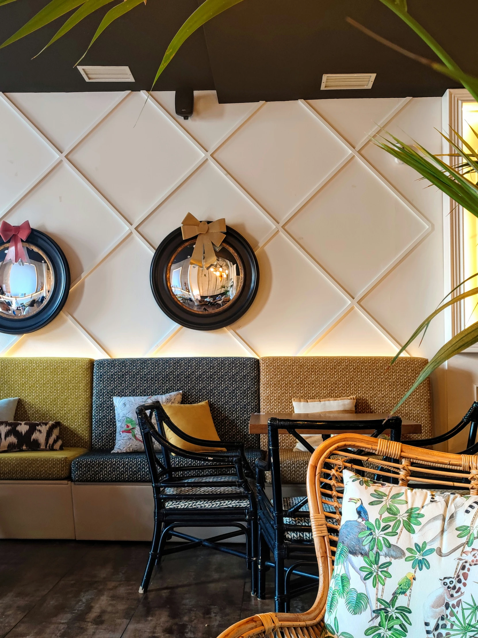 a white tiled wall has several chairs and mirrors