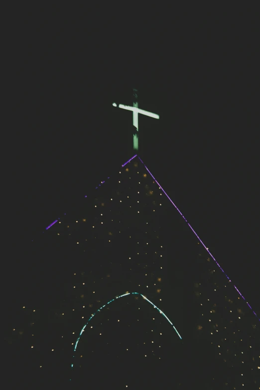 a tall cross atop a dark church steeple