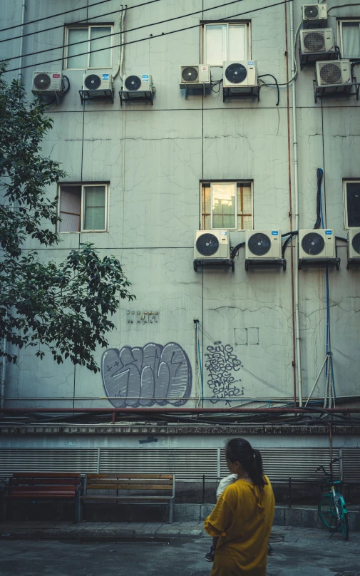 a person in yellow jacket walking in front of a building with graffiti