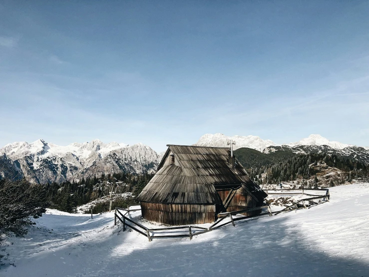 a thatch house is seen on a snow covered slope