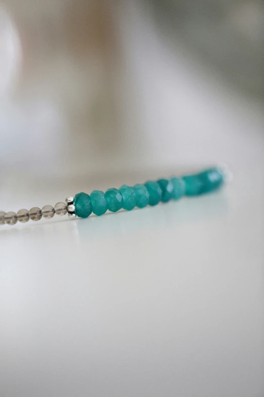 an image of a turquoise bead in the shape of the letter s