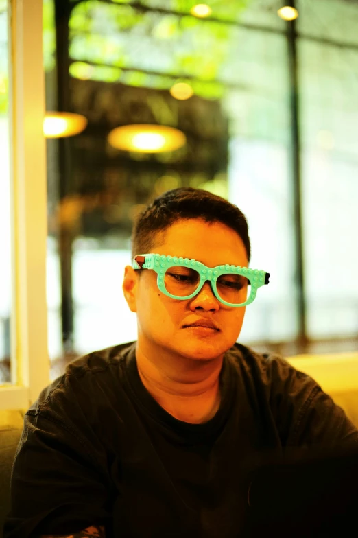 young man wearing shades sitting by a computer