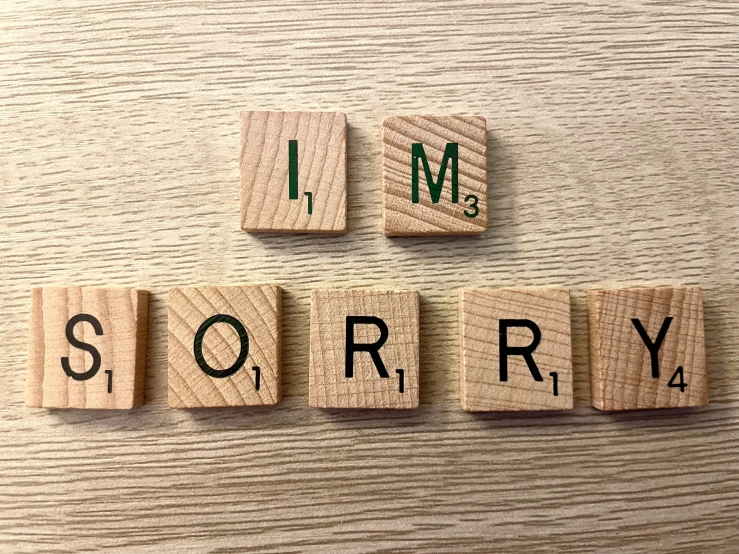 i'm sorry word made of wood blocks on top of a wooden desk