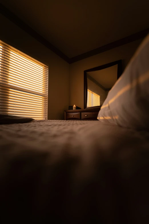 a bed in a bedroom with the sheets down and a window covered in blinds