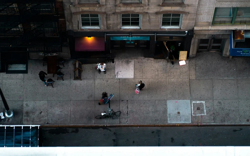 a group of people walking on the sidewalk in front of buildings