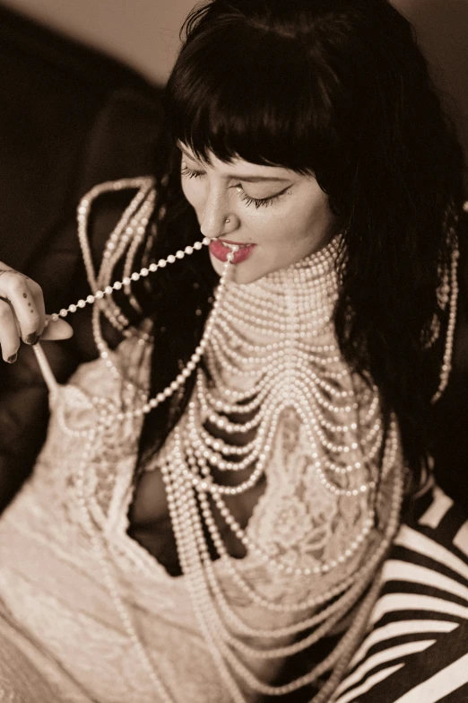 a woman wearing pearls and lipstick biting on a string