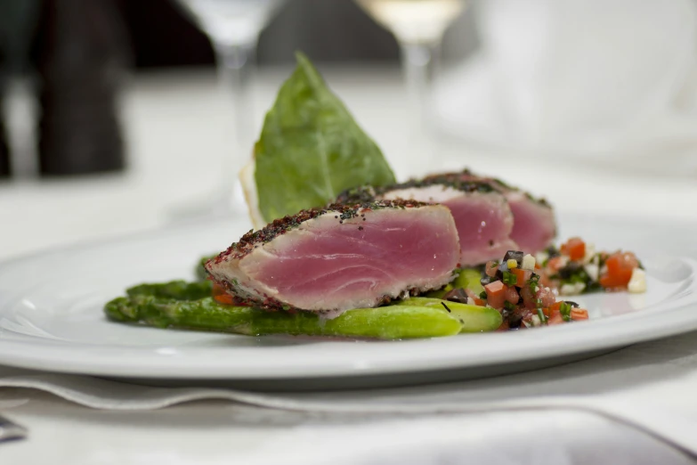 a white plate filled with meat, vegetables and a wine glass