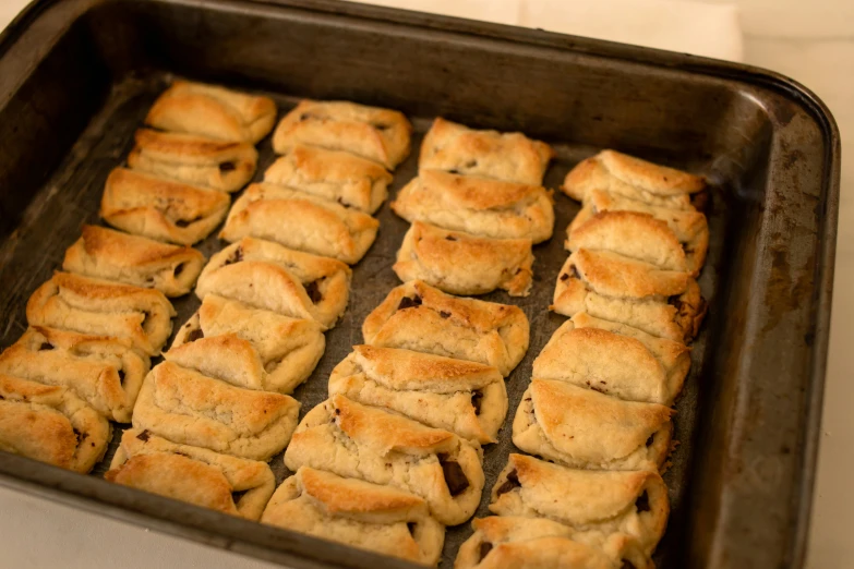 pastries resting in a square cookie tin on a stove top