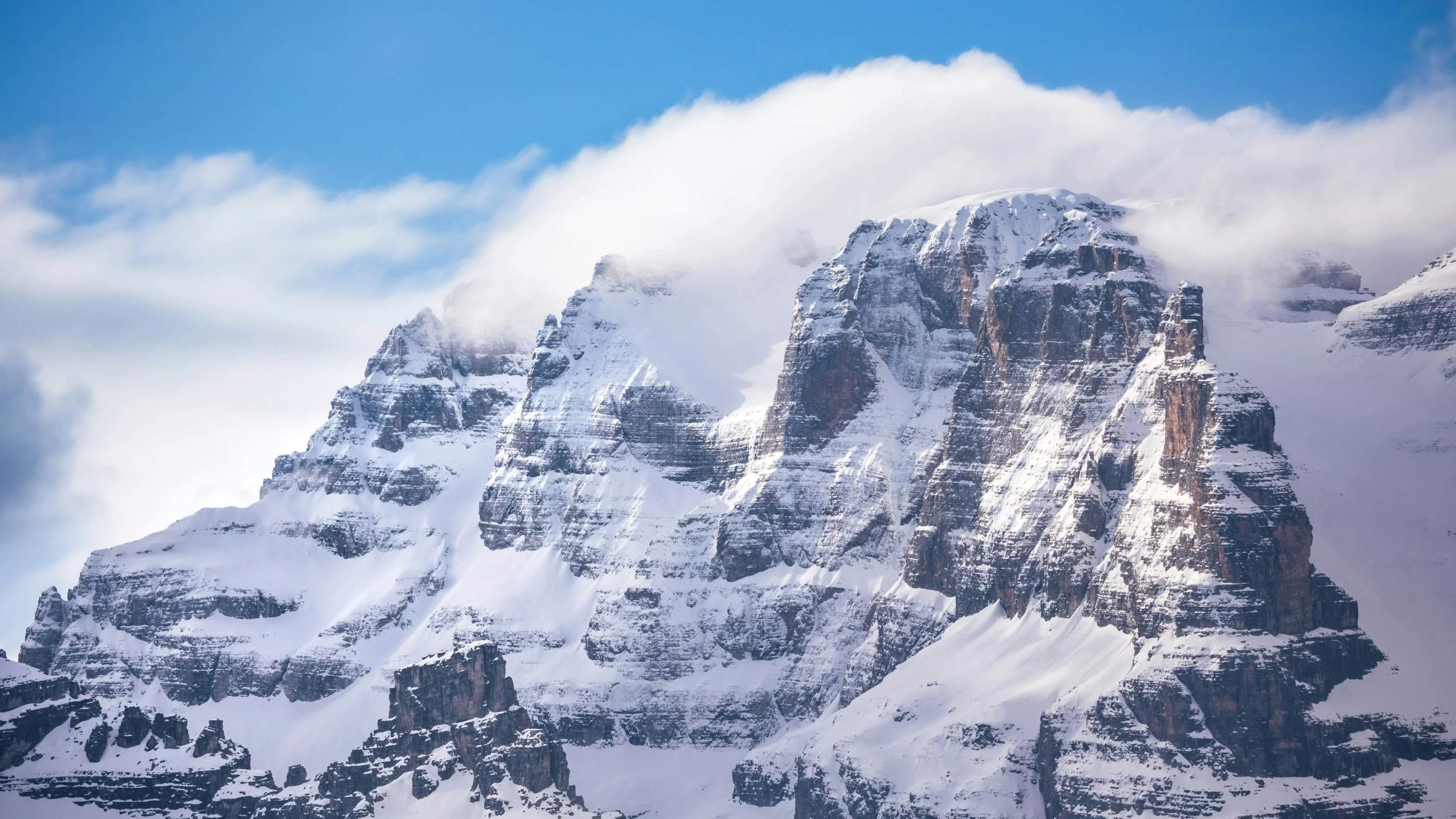 a mountain with snow and clouds in the distance