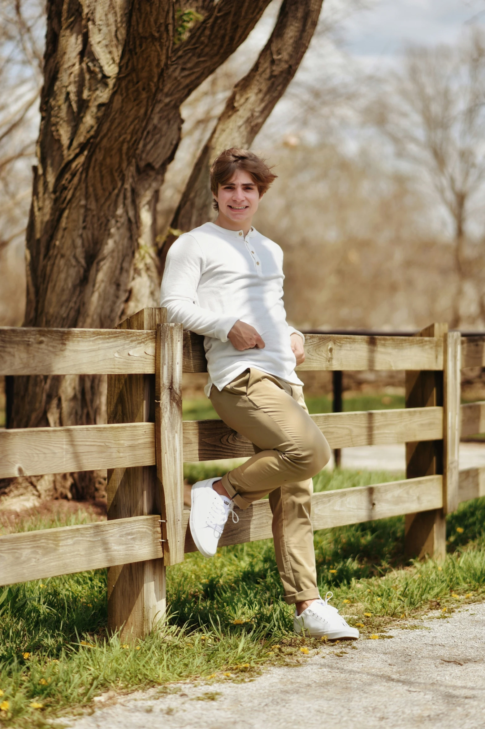 a man leaning against a wooden fence on a grass covered field