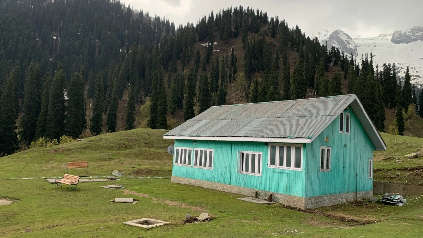 a small blue cabin with some trees around it