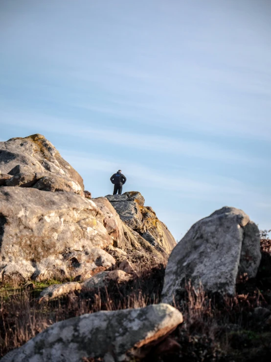 a lone person is standing on a rock top