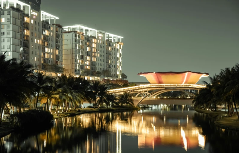 a large tall building next to a river in front of a city