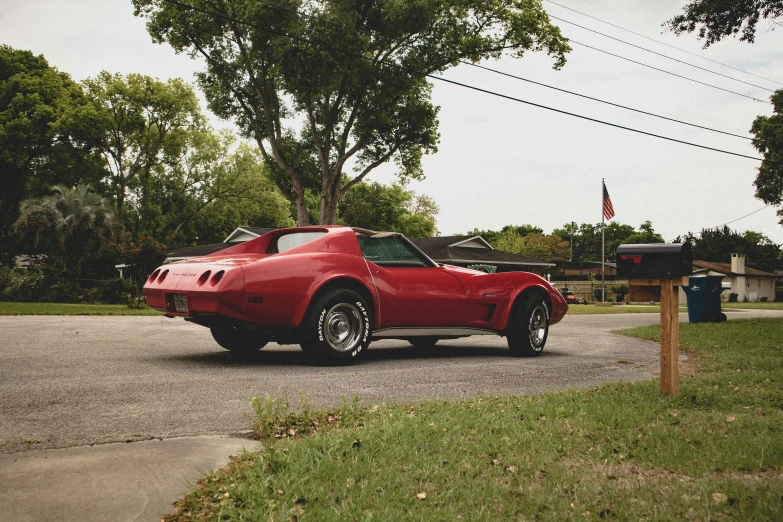 a red corvette corvette sitting on the side of the road