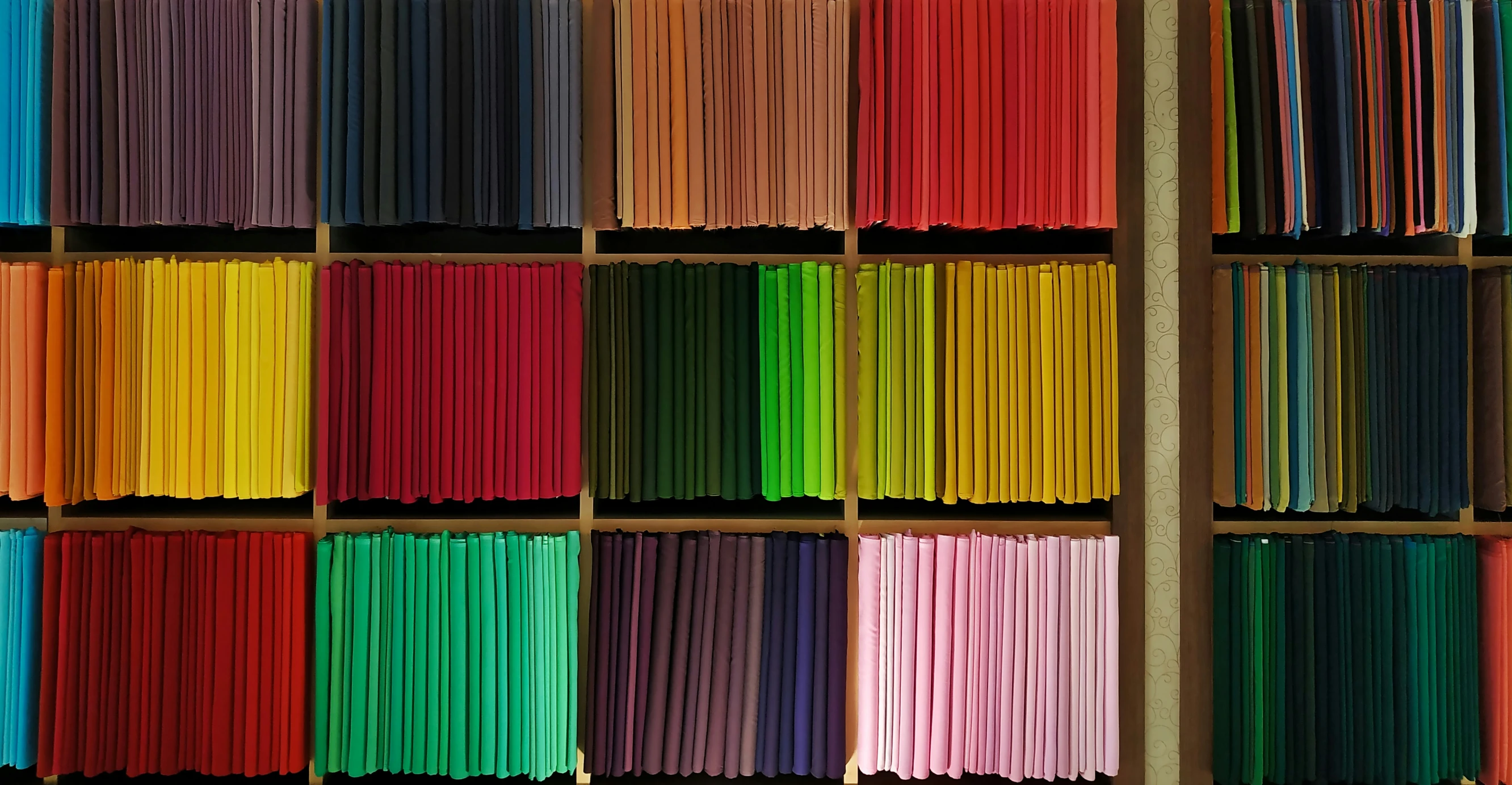 multiple bookshelves with rows of colorful colored books