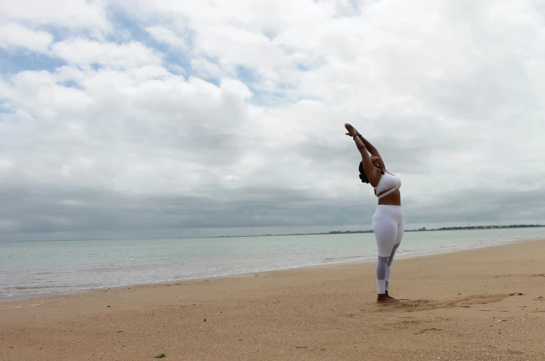 a woman stretches as she stands on her back on the beach