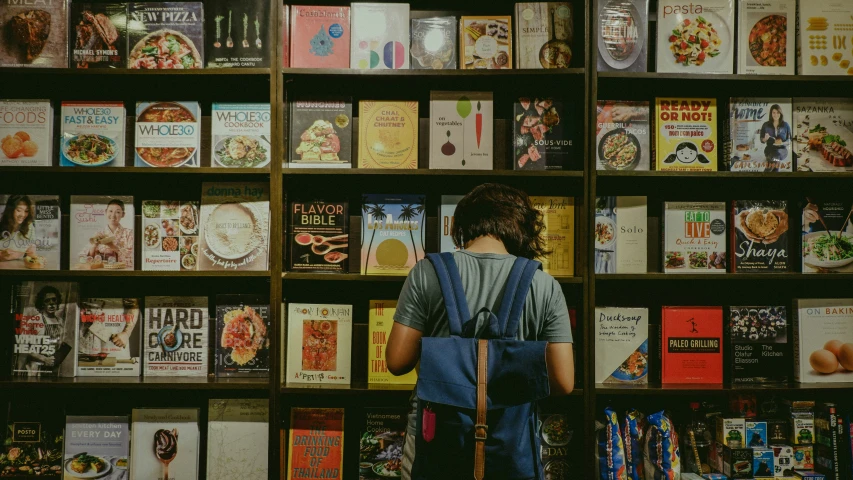 person in a liry reading a book behind a wall of books