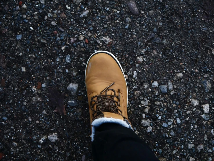 a person walking across the ground wearing brown shoes