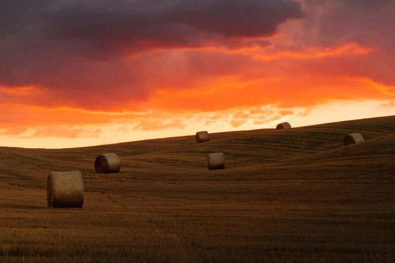 some hay bails are in a field and some dark clouds