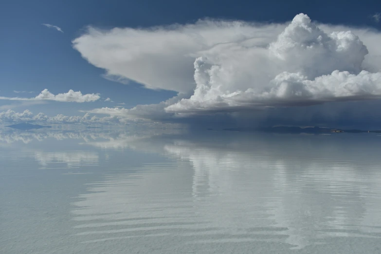 a large cloud is flying above the ocean water