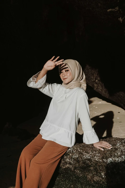 a woman in a hijab is posing on a rock