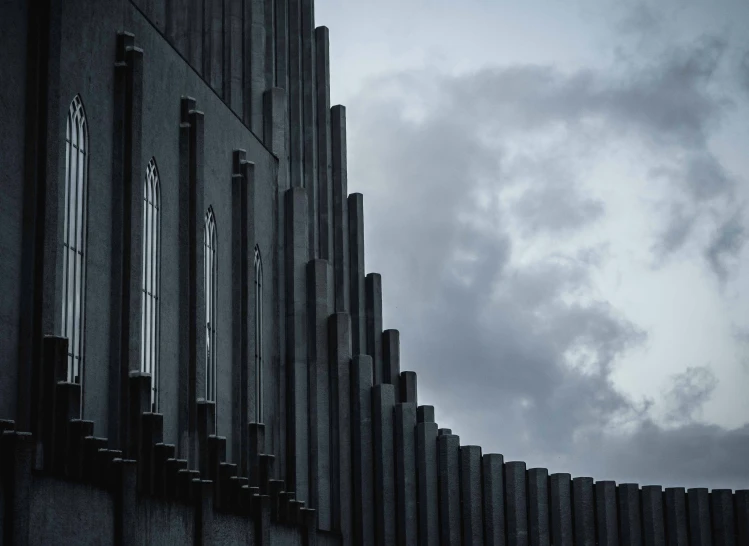 a grey wall with several metal bars and the clouds