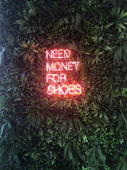 a neon sign reads need money top shoes