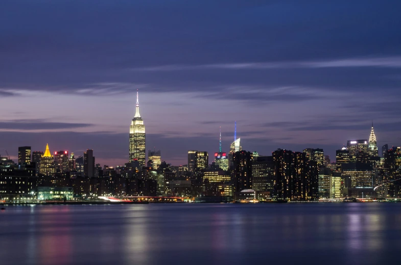 the city is lit up at night with the empire building in the foreground