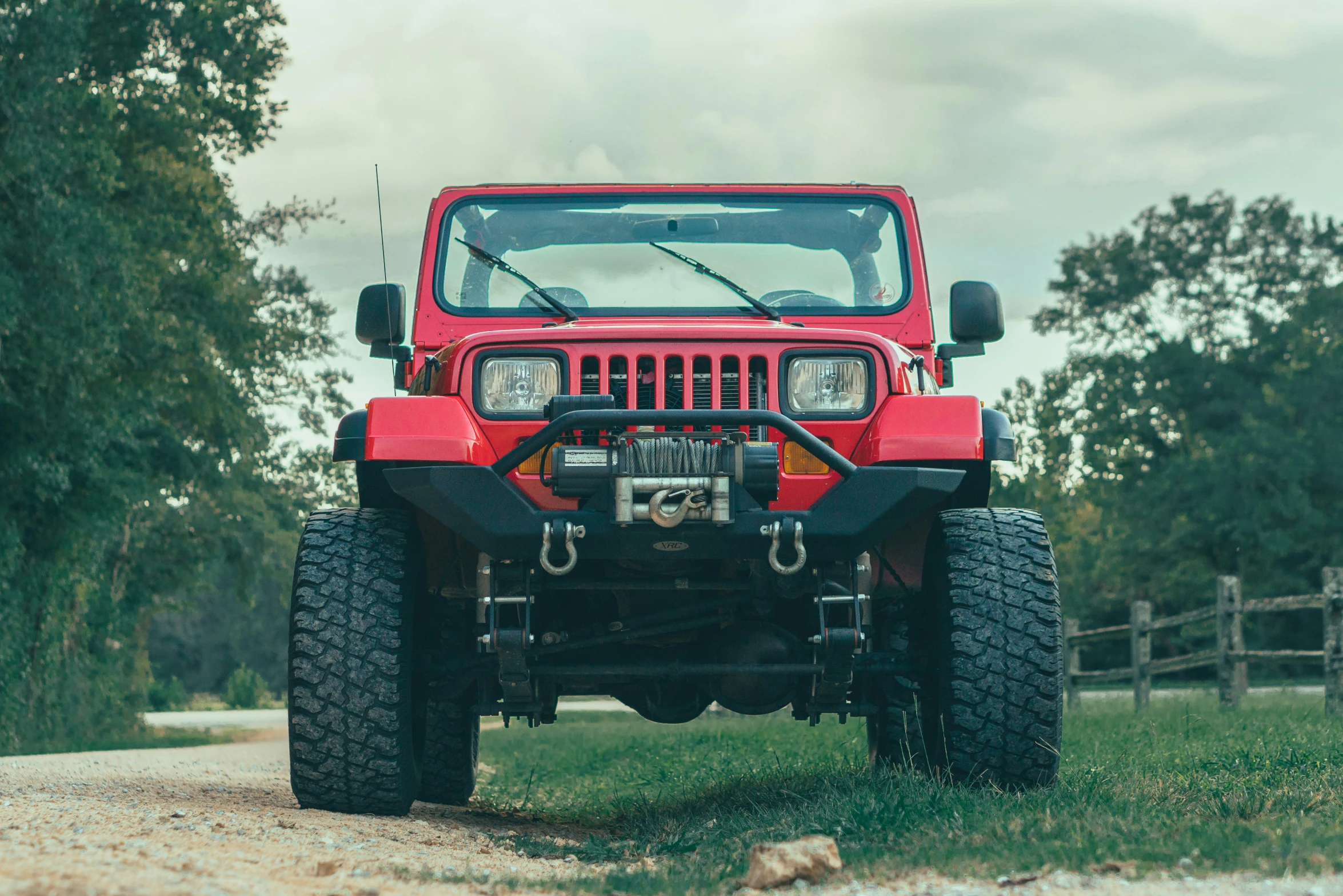 a red jeep is parked on a road