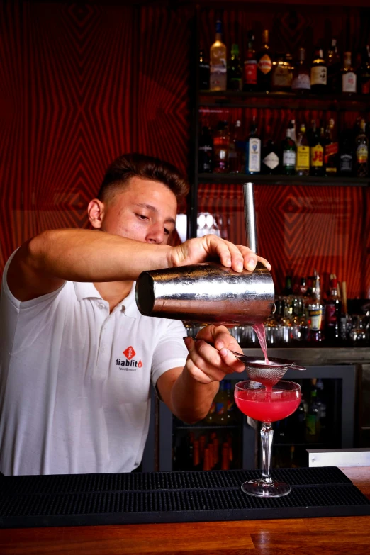 the bartender is mixing a drink in the tall glass