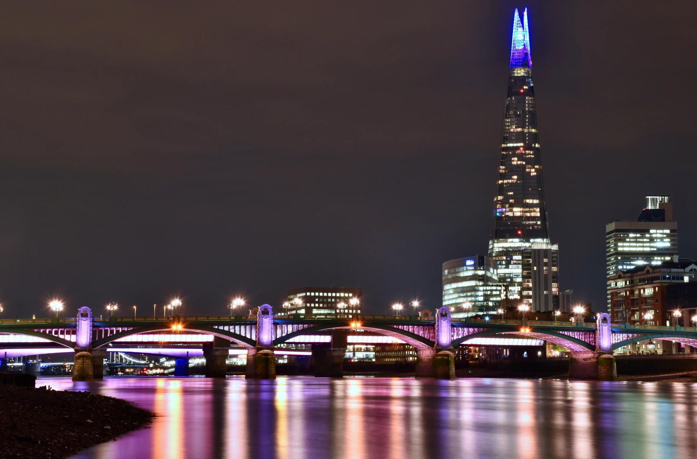 an illuminated building stands in front of the city at night