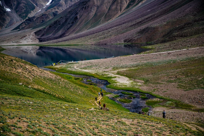 the mountain is green and brown and the people walk