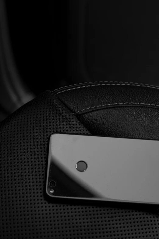 a closeup of a black leather chair and the back part with an aluminum plate attached