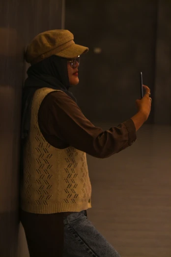 a person leaning against a wall looking at a cell phone