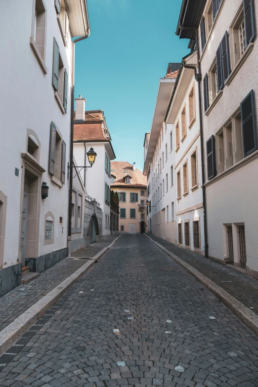 a cobblestone street in old town with white buildings