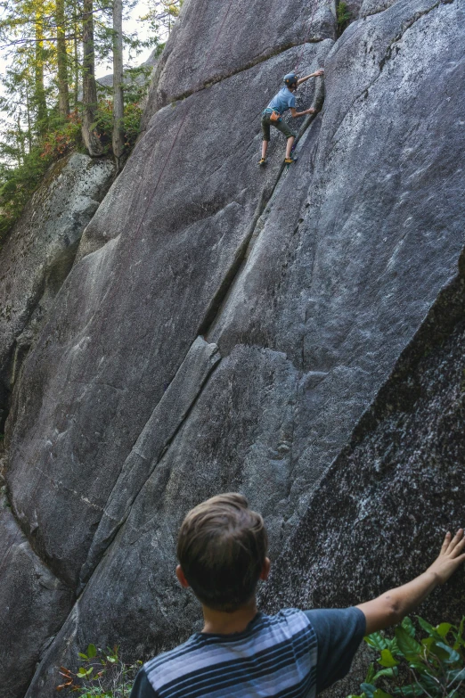 the man on the rocks is pointing toward the rock climber