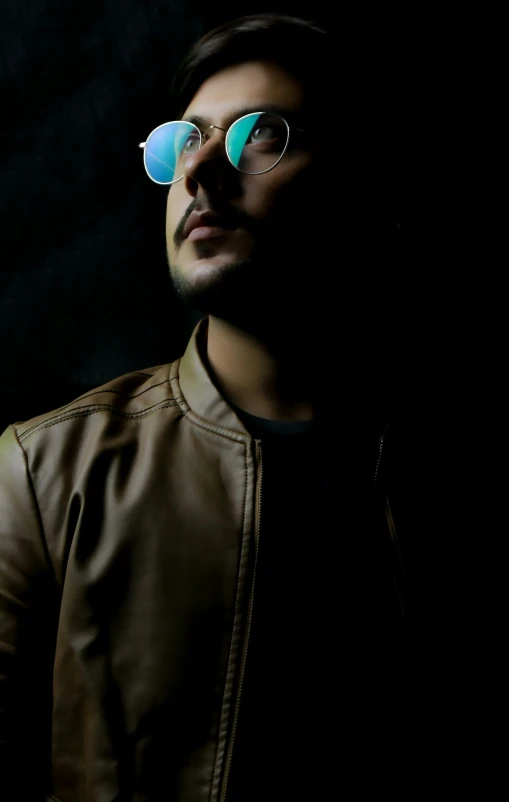 man wearing glasses, standing against black background