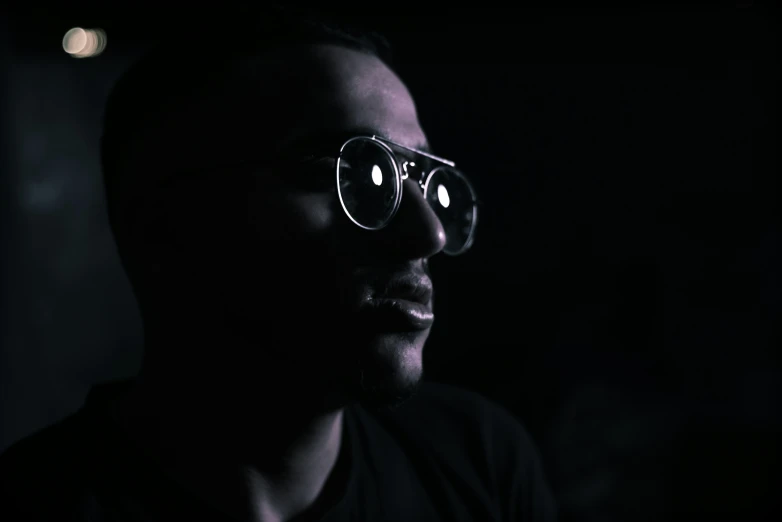 a man in dark lighting with glowing glasses on