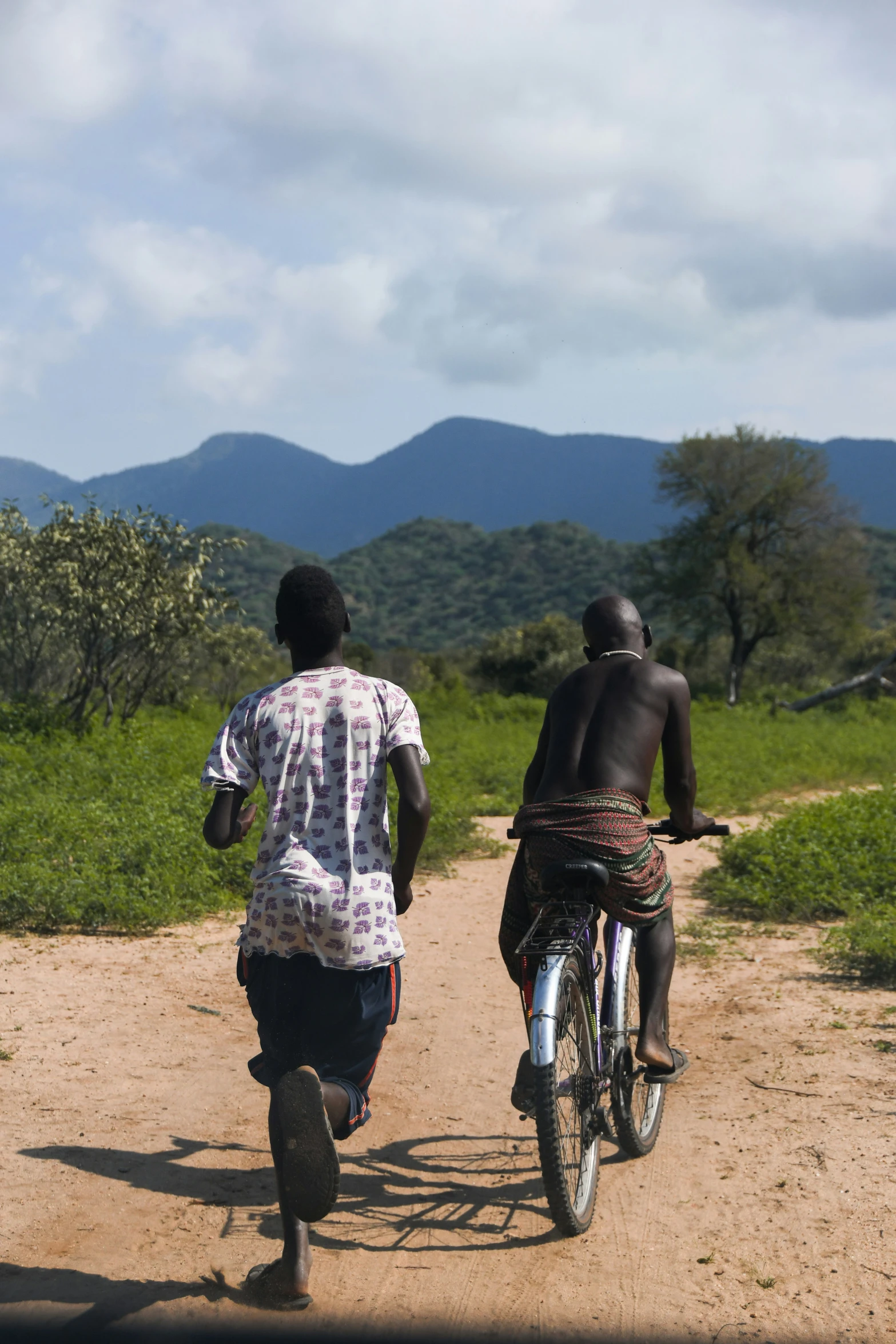 a man is running with his bicycle as another walks