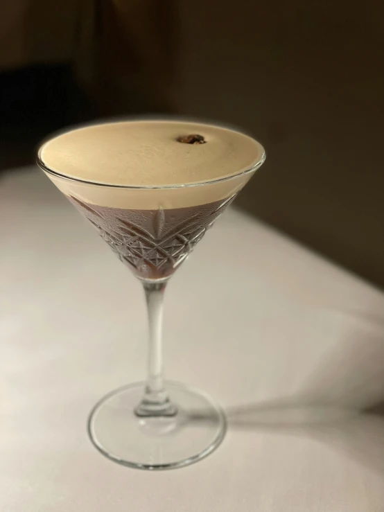 an empty martini glass sitting on top of a white table