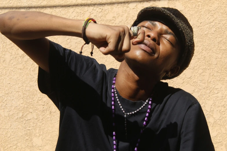 young man wearing beads and a hat with his eyes closed