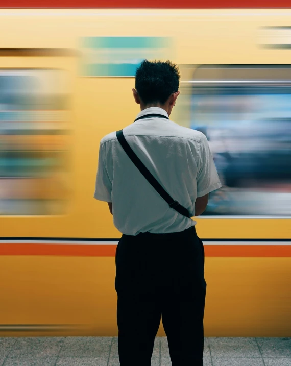 man looking out at a train with motion blur behind him